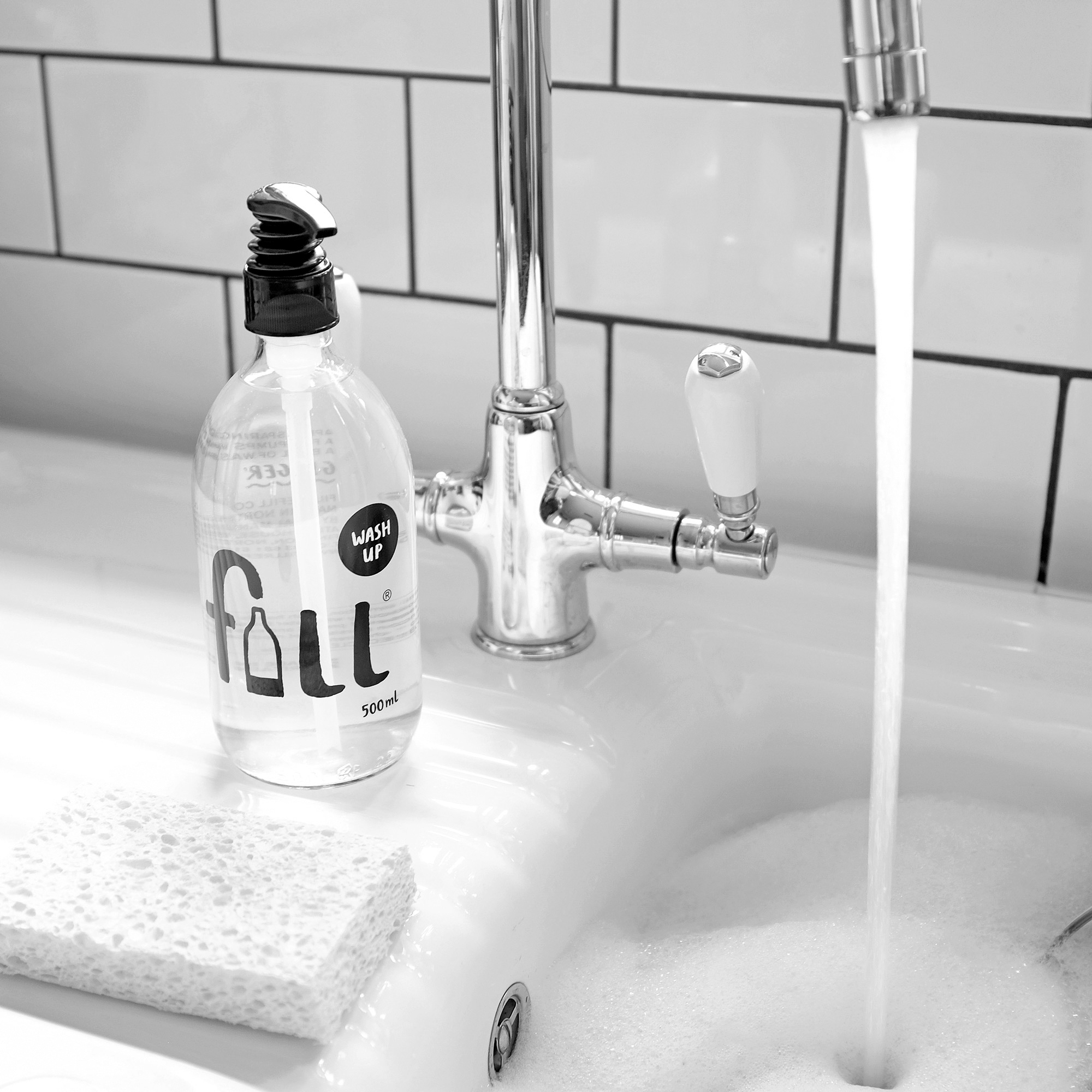 Fill refill Wash Up glass bottle next to a kitchen sink and sponge