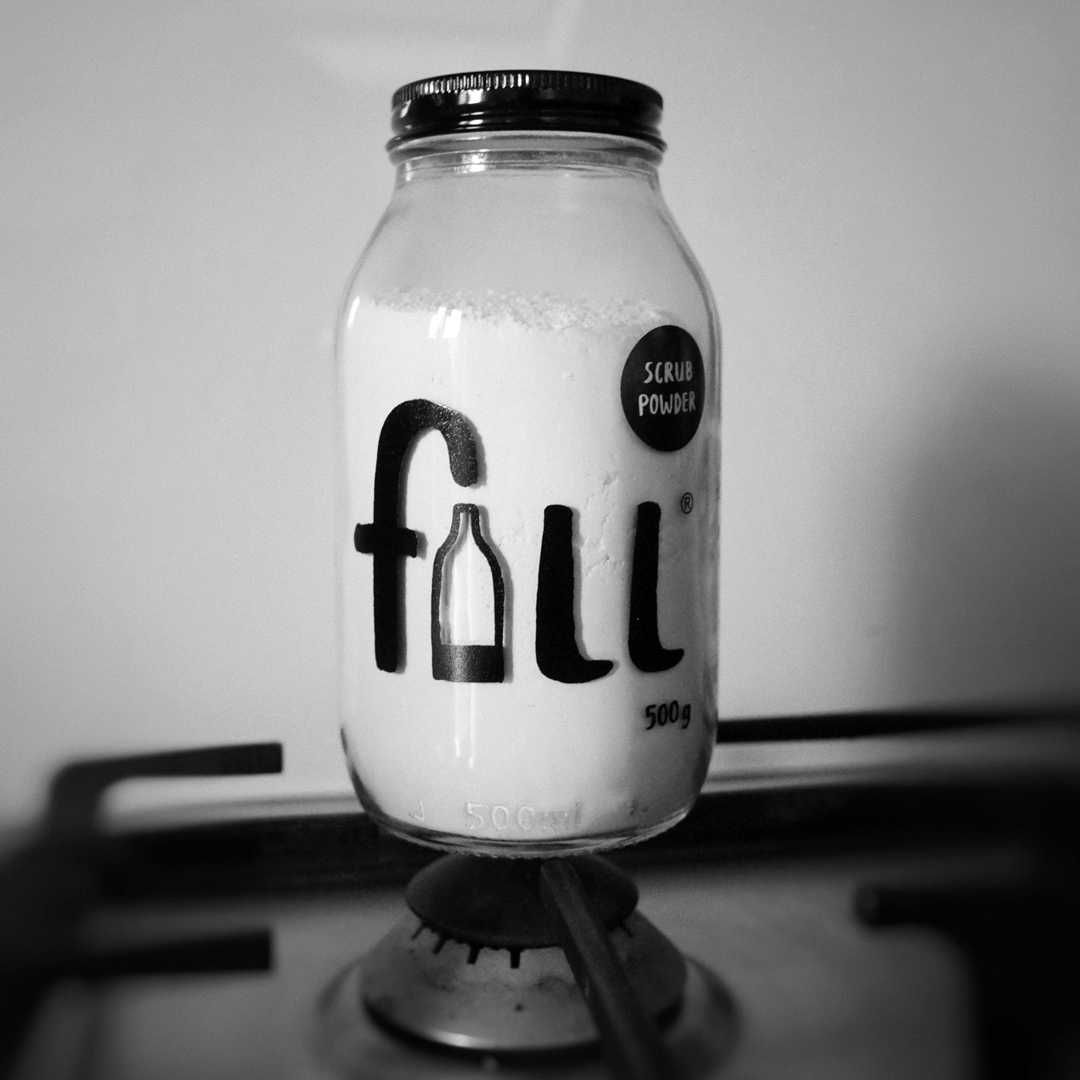 Fill Scrub powder jar standing on top of a kitchen hob