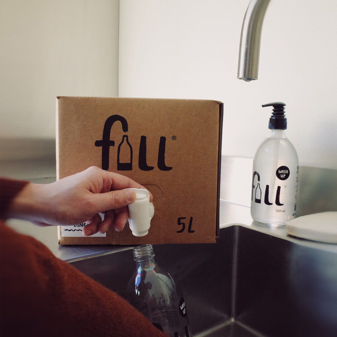Person refilling a bottle of Fill Wash Up from a 5L bag in box